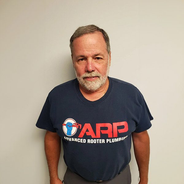 A man in a t-shirt standing against the wall.